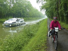 Mann fährt auf einem Fahrrad neben einem Fluss