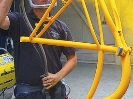 Mann lackiert Fahrradrahmen